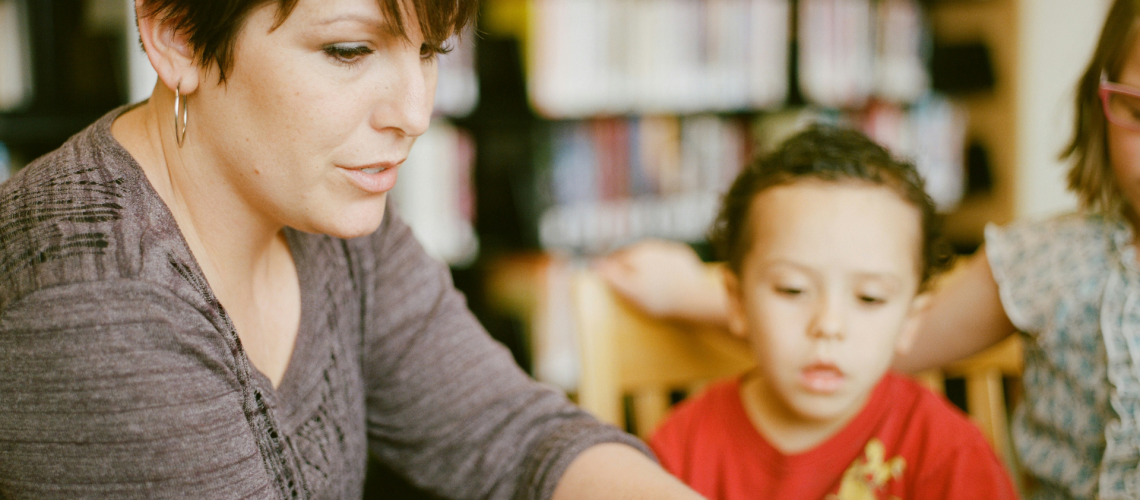 Caring adult and child talking at a school table — building trust and safety for child sexual abuse prevention.