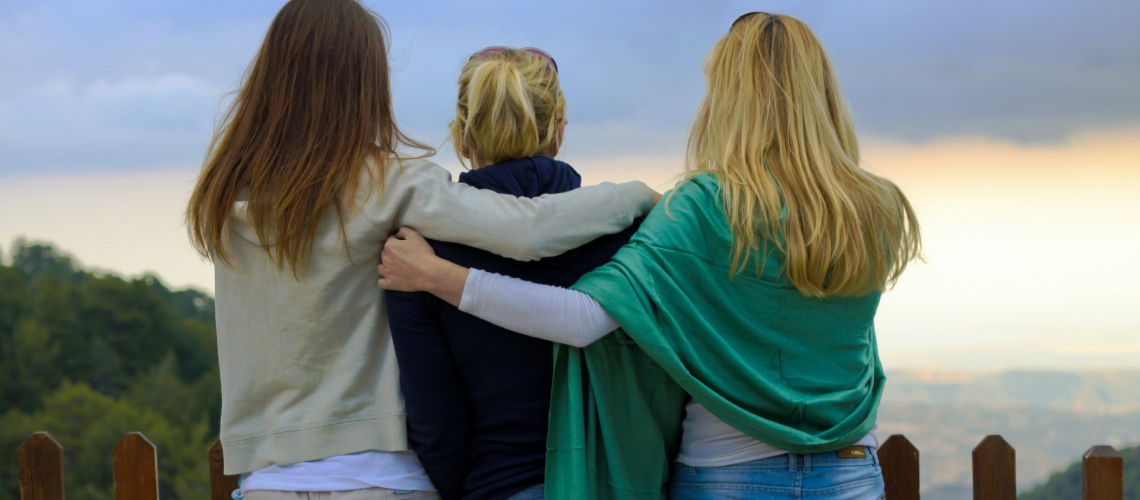 Three women stand together with arms around each other, symbolizing support and hope during Domestic Violence Awareness Month